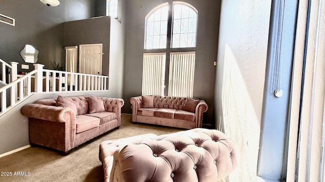 living room featuring a towering ceiling and light colored carpet