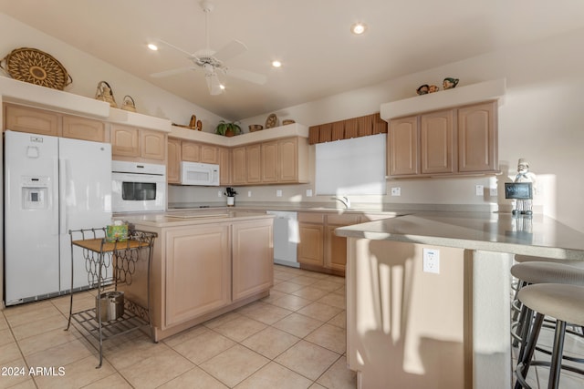 kitchen featuring kitchen peninsula, a kitchen breakfast bar, light brown cabinetry, white appliances, and lofted ceiling