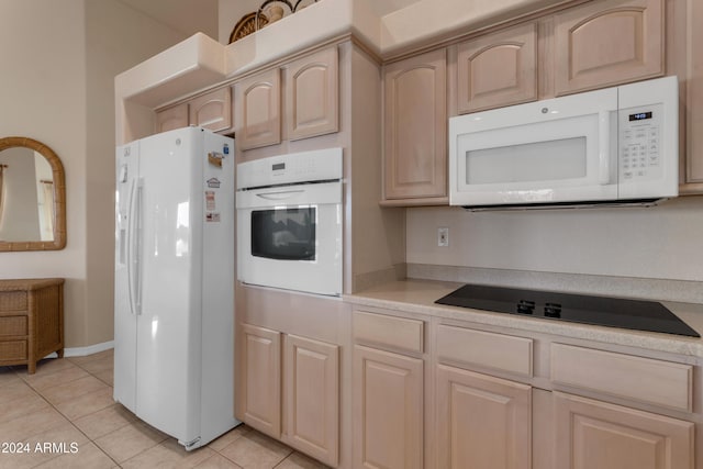 kitchen with light brown cabinets, light tile patterned flooring, and white appliances