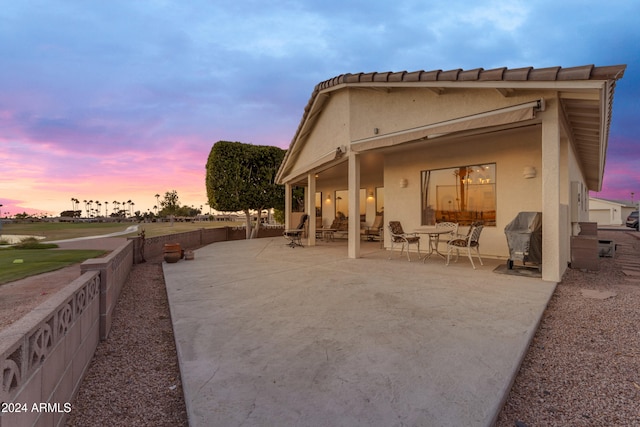 back house at dusk featuring a patio area