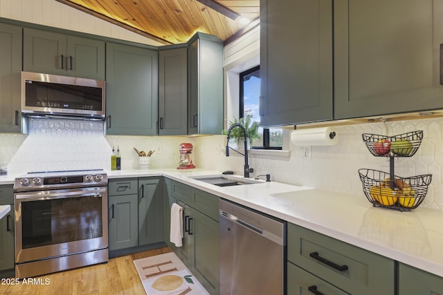 kitchen featuring appliances with stainless steel finishes, a sink, tasteful backsplash, light countertops, and wood ceiling