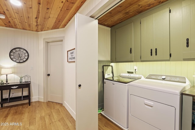 laundry area featuring washing machine and dryer, cabinet space, wooden ceiling, and light wood-style floors