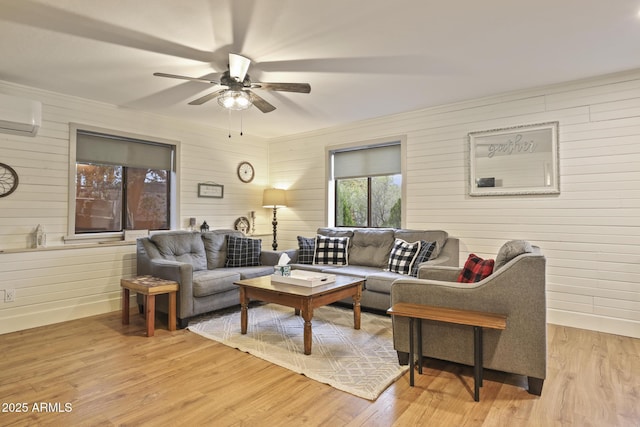 living area with ceiling fan, wooden walls, wood finished floors, a wall mounted AC, and baseboards