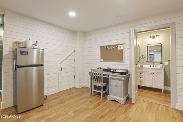office with light wood-style flooring, a sink, and wooden walls
