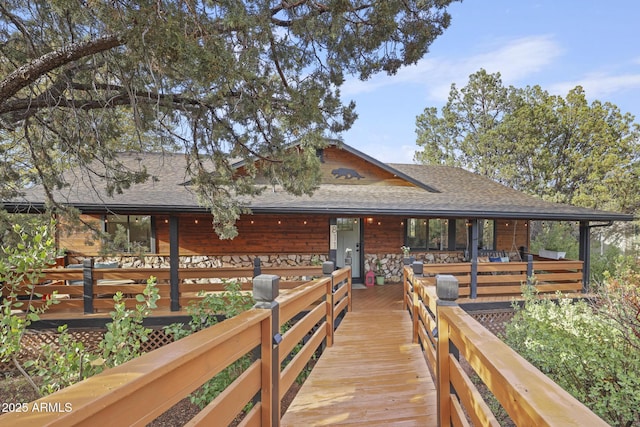 back of house featuring a shingled roof and a wooden deck