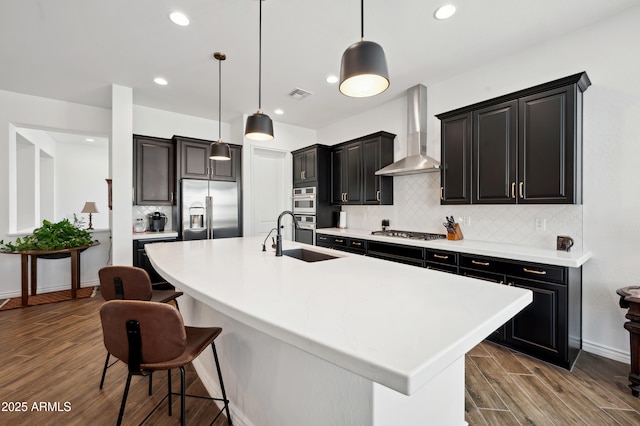 kitchen with wall chimney exhaust hood, stainless steel appliances, a large island, and pendant lighting