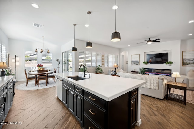 kitchen with sink, a wealth of natural light, hanging light fixtures, and a center island with sink