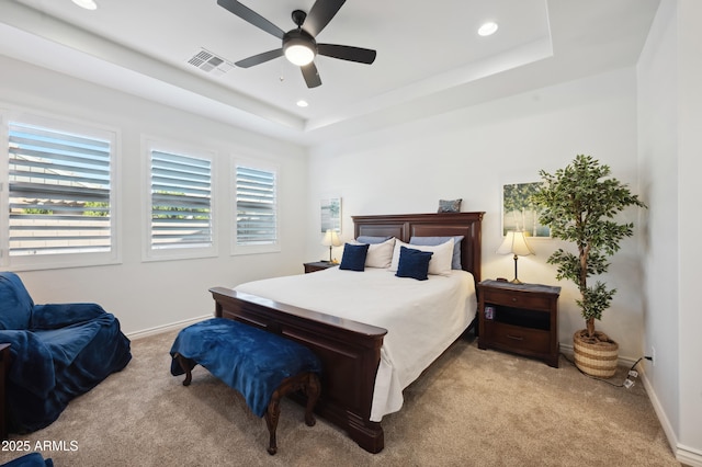 bedroom featuring ceiling fan, a raised ceiling, and light carpet