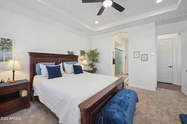 carpeted bedroom featuring ceiling fan, connected bathroom, and a raised ceiling