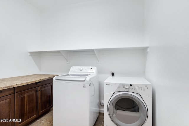 laundry room with light tile patterned floors, washer and clothes dryer, and cabinets