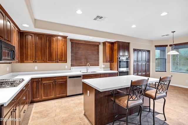 kitchen with sink, a breakfast bar area, hanging light fixtures, a center island, and stainless steel appliances