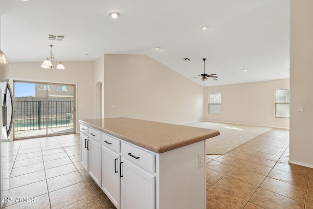 kitchen with lofted ceiling, white cabinetry, a center island, decorative light fixtures, and light colored carpet