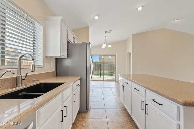 kitchen featuring lofted ceiling, sink, light tile patterned floors, white cabinetry, and hanging light fixtures