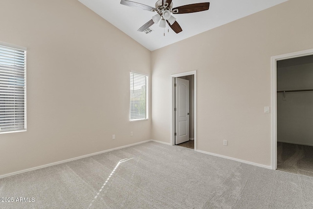 unfurnished bedroom with vaulted ceiling, a spacious closet, light carpet, and ceiling fan