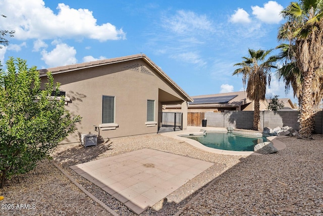 rear view of property featuring a fenced in pool and a patio