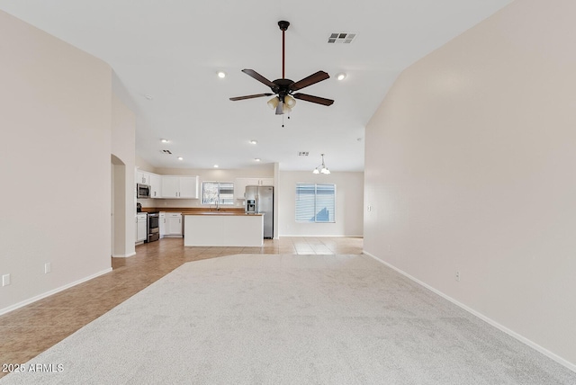 unfurnished living room with sink, light tile patterned floors, high vaulted ceiling, and ceiling fan