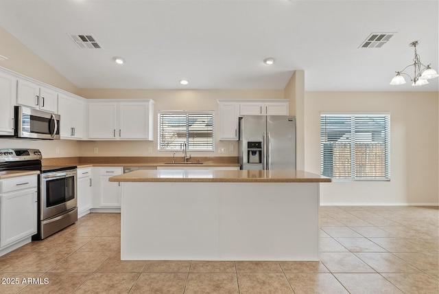 kitchen featuring stainless steel appliances, a center island, pendant lighting, and white cabinets