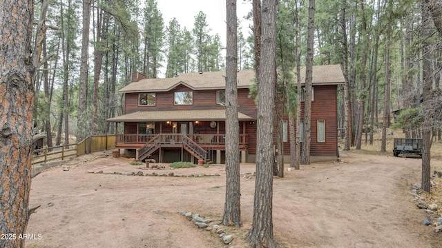 chalet / cabin featuring covered porch, fence, driveway, stairway, and a chimney