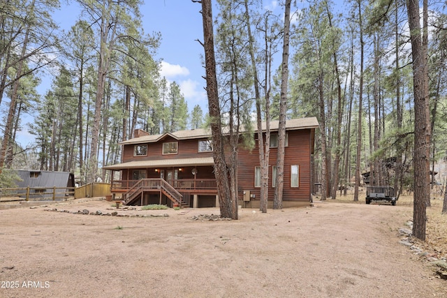 rear view of property featuring driveway, a chimney, and fence