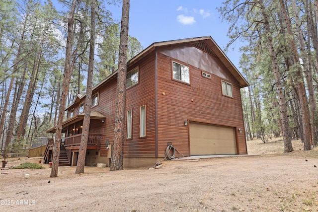 view of property exterior featuring a garage, driveway, stairway, and a wooden deck