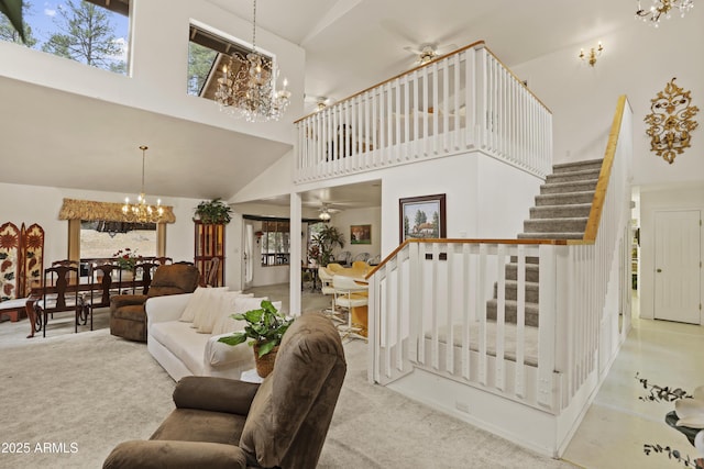 carpeted living area featuring stairs, a high ceiling, and ceiling fan with notable chandelier