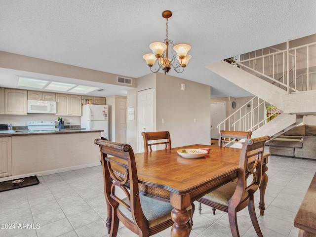 dining room featuring a chandelier, a textured ceiling, and light tile patterned floors