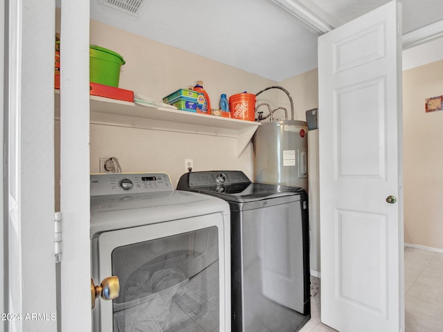 laundry room featuring water heater, separate washer and dryer, and light tile patterned floors