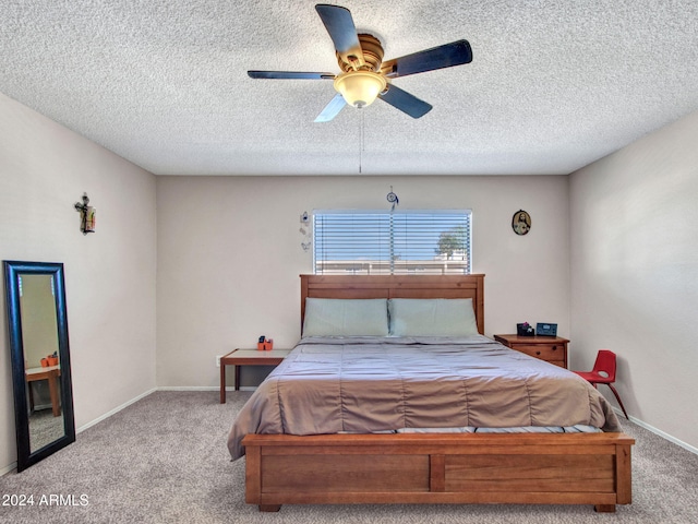 bedroom featuring a textured ceiling, light colored carpet, and ceiling fan