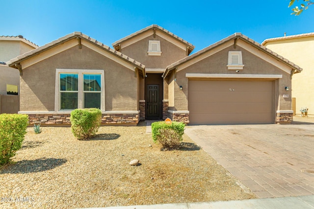 5218 W Lydia Ln, Laveen, AZ 85339 - view of front of house with stucco siding, stone siding, decorative driveway, a garage, and a tiled roof