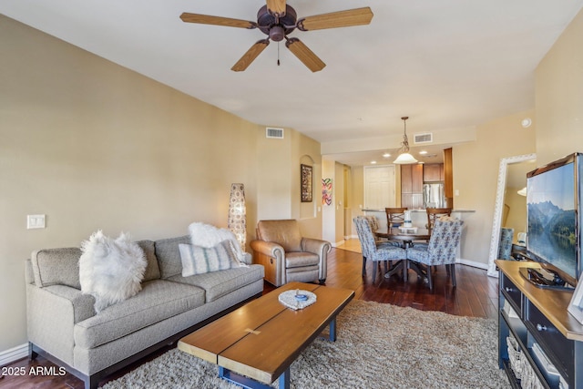 living room featuring dark wood-type flooring and ceiling fan