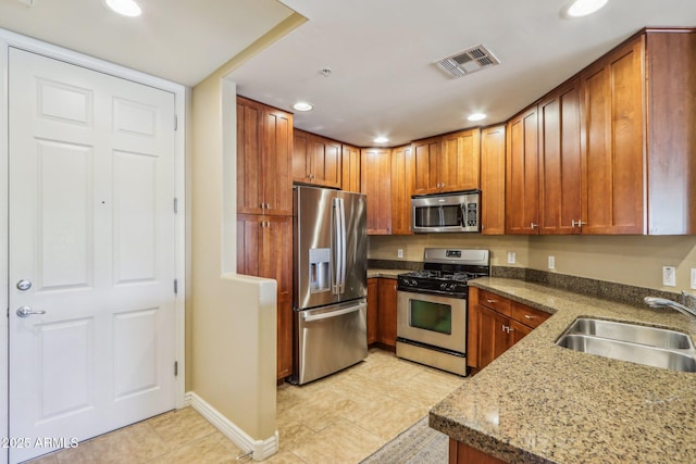 kitchen with sink, light tile patterned floors, stainless steel appliances, and light stone countertops