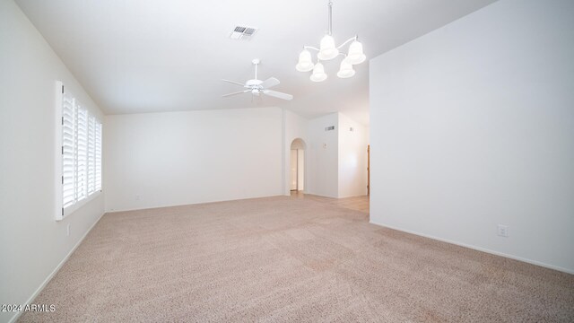 carpeted spare room with ceiling fan with notable chandelier and lofted ceiling