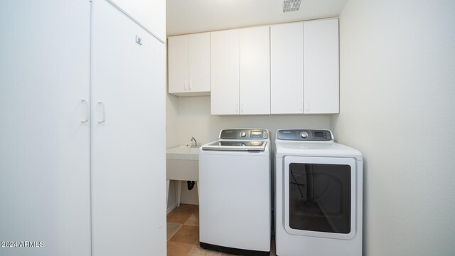 clothes washing area featuring light tile patterned flooring, cabinets, and independent washer and dryer