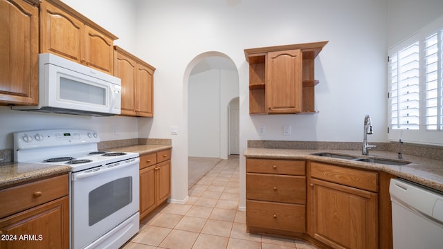 kitchen featuring light tile patterned flooring, white appliances, and sink