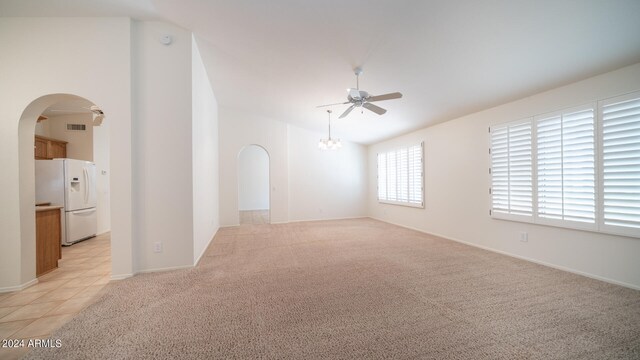 carpeted empty room with ceiling fan with notable chandelier and lofted ceiling