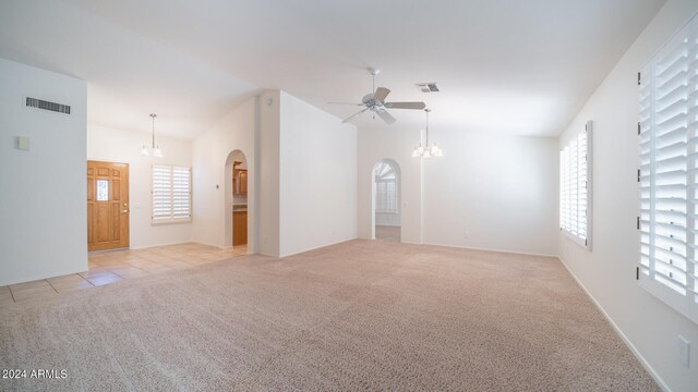 spare room featuring light carpet and ceiling fan with notable chandelier