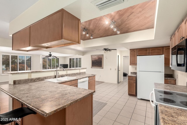 kitchen with a raised ceiling, ceiling fan, a sink, and white appliances