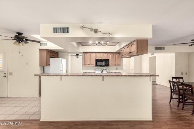 kitchen with black microwave, visible vents, a ceiling fan, and freestanding refrigerator