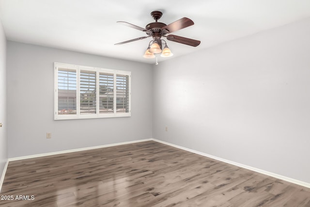 spare room featuring baseboards, wood finished floors, and a ceiling fan