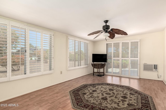 living area featuring a ceiling fan, an AC wall unit, and wood finished floors