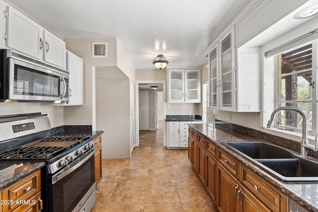 1749 W Monterosa St, Phoenix, AZ 85015 - kitchen with appliances with stainless steel finishes, white cabinetry, glass insert cabinets, and dark stone countertops