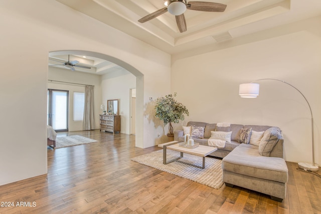 living room with a raised ceiling, hardwood / wood-style floors, and ceiling fan