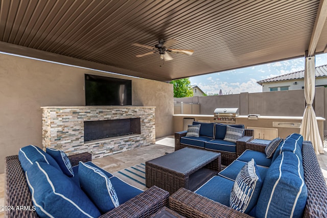 view of patio featuring ceiling fan, grilling area, an outdoor living space with a fireplace, and exterior kitchen