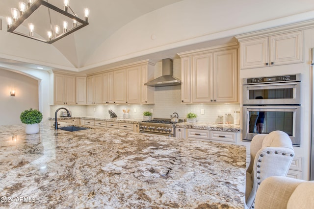 kitchen featuring lofted ceiling, sink, wall chimney exhaust hood, stainless steel appliances, and a kitchen bar