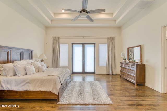 bedroom featuring ceiling fan, a raised ceiling, dark hardwood / wood-style floors, and french doors