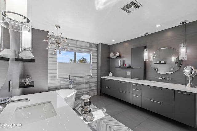 full bathroom with tile patterned flooring, vanity, visible vents, a freestanding bath, and tile walls