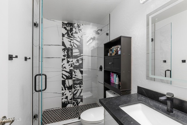 bathroom with toilet, a shower stall, and vanity