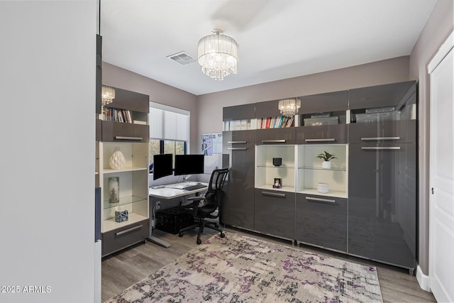 office area featuring light wood-style floors, visible vents, and a notable chandelier