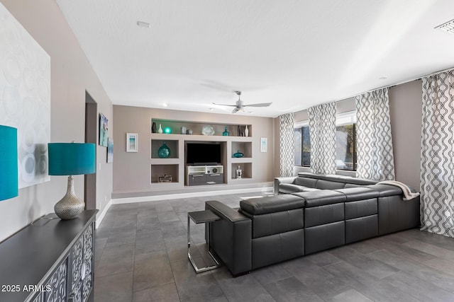 living room with built in shelves, a ceiling fan, and baseboards