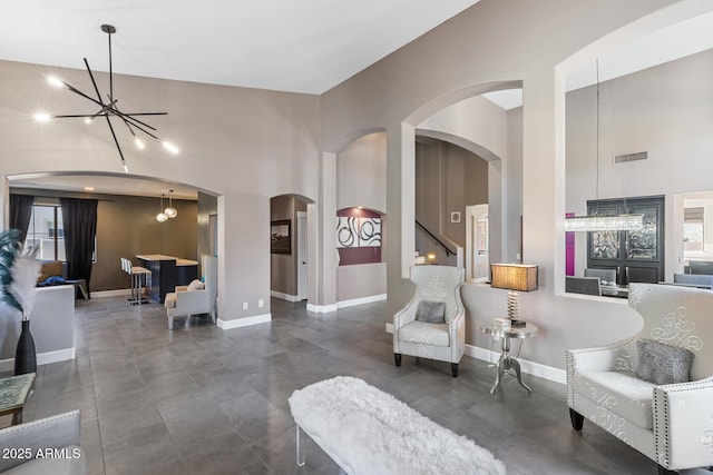 sitting room featuring arched walkways, baseboards, visible vents, and a high ceiling